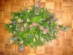 Grafstuk met pauwenveren, blauwe anemoon, dennengroen, lila hyacint, lila freesia